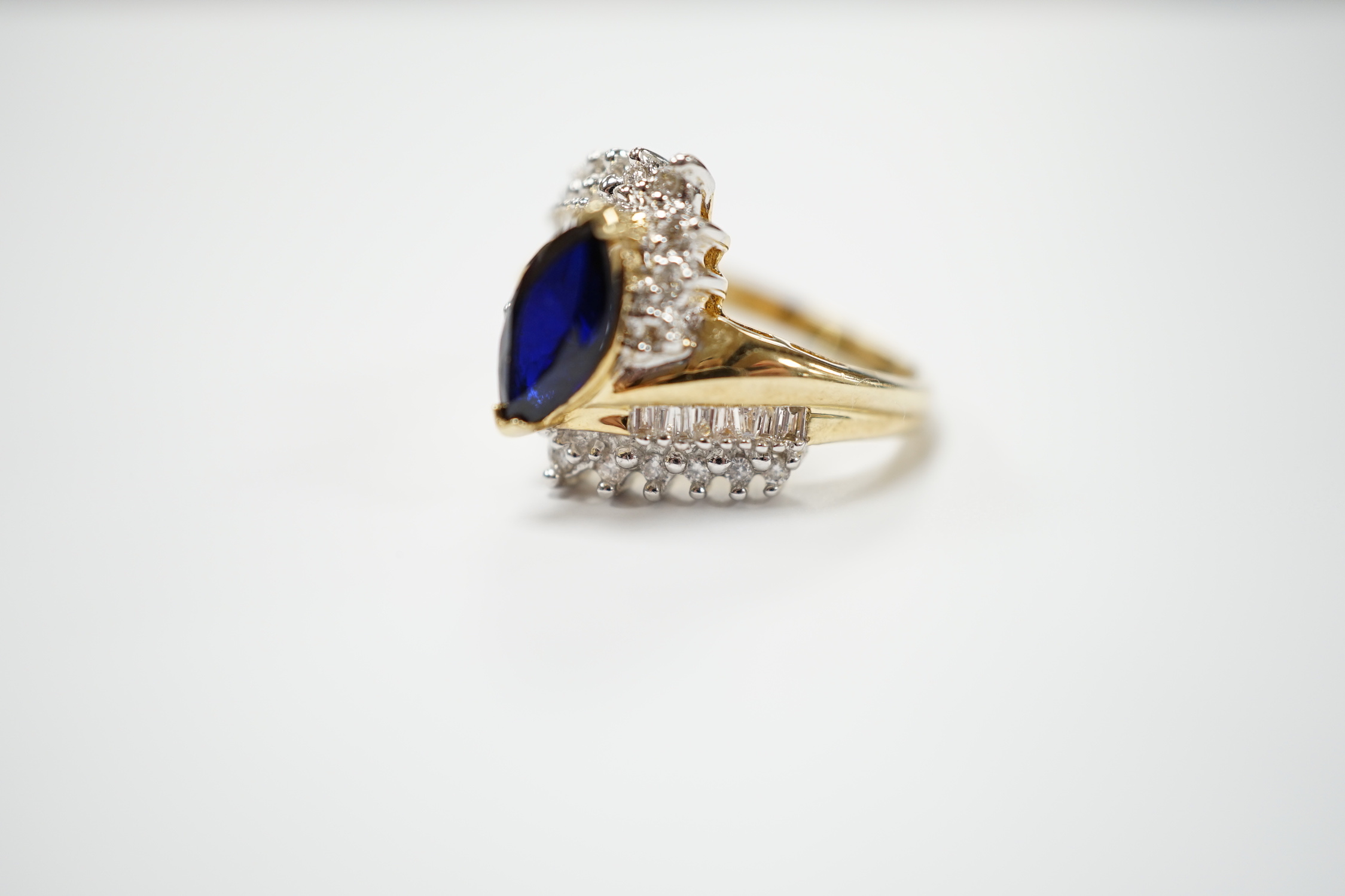 A modern 14k and single stone marquise cut sapphire and diamond chip cluster set crossover dress ring, size M, gross weight 5.3 grams.